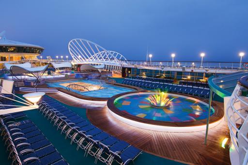 The deck of Royal Caribbean's Enchantment of the Seas with a pool and deck chairs. 